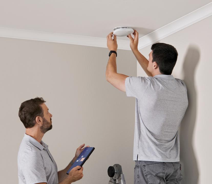 Engineer installing a Wi-Fi access point with cabling and a laptop